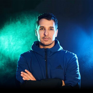 WEBgarten - Webdesign - Braunau | Porträt von Nisar Zidi vor einem grün-blauen Hintergrund für die Website der Fußball-Talenteschmiede, ein Referenzprojekt von WEBgarten.